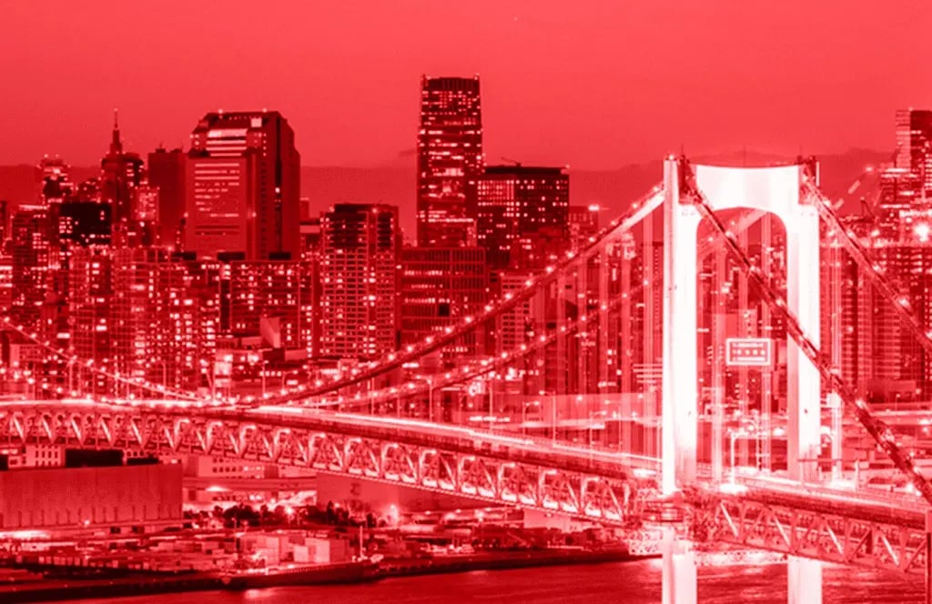Panorama of a Japanese metropolis at night with illuminated skyscrapers and a large bridge in the foreground.